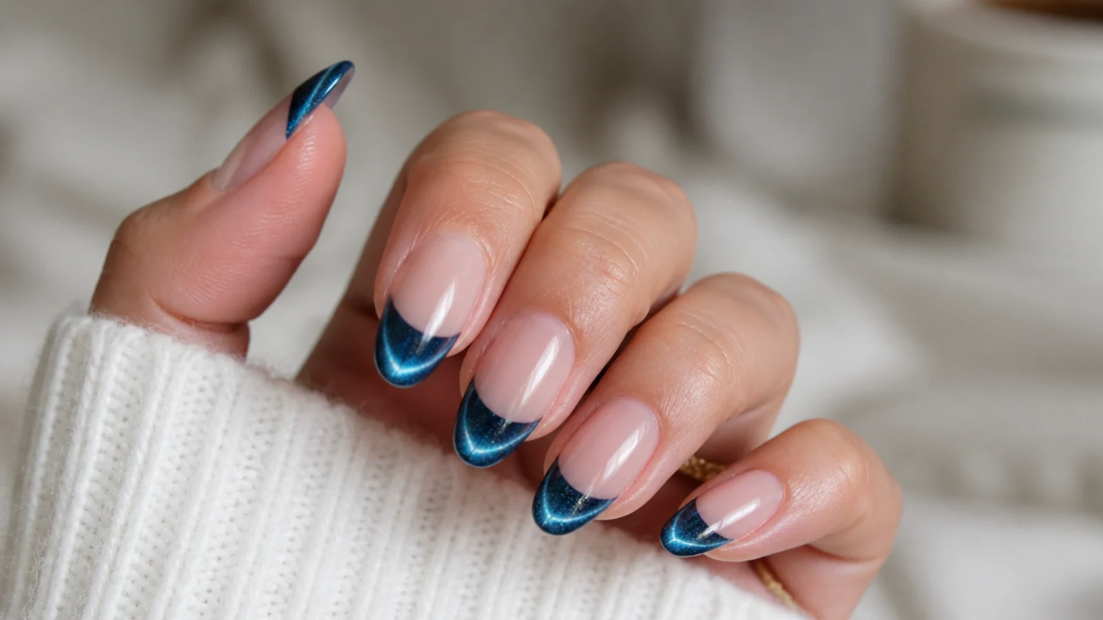 Blue cat eye french tip nails with a bright magnetic light stripe across the tips on almond nails