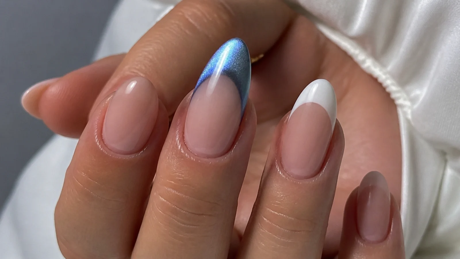 A glowing blue cat eye tip beside a flat white classic french tip