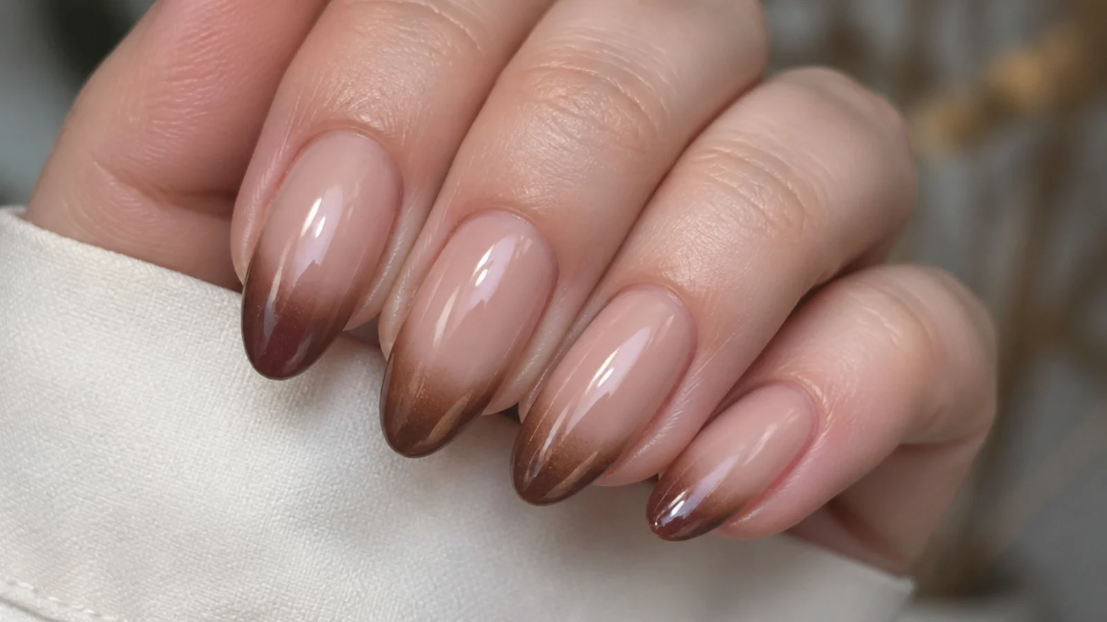 Nude base fading into a brown cat eye french tip with soft gradient
