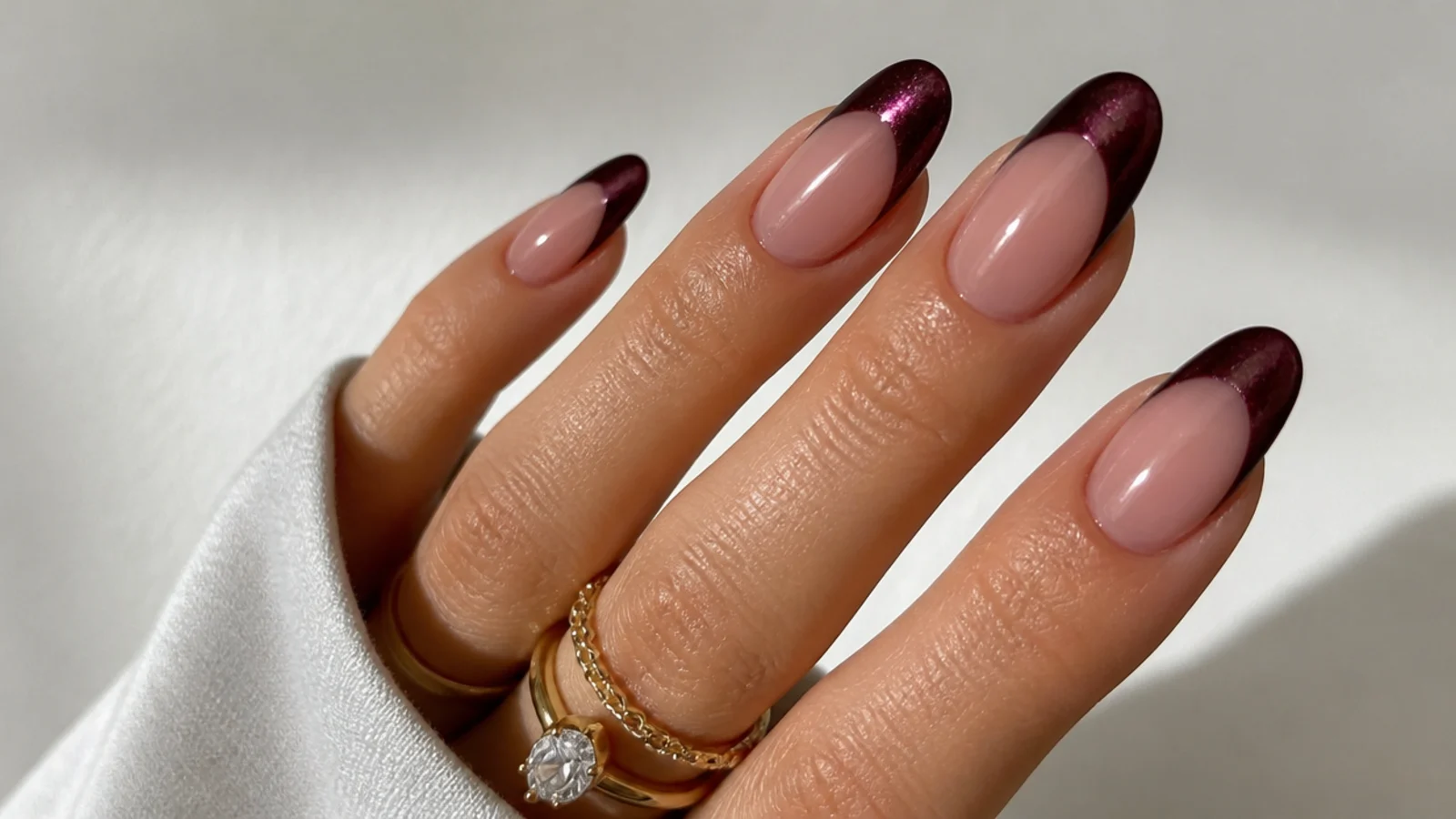 Deep plum-brown cat eye french tips with a jewel-toned glow
