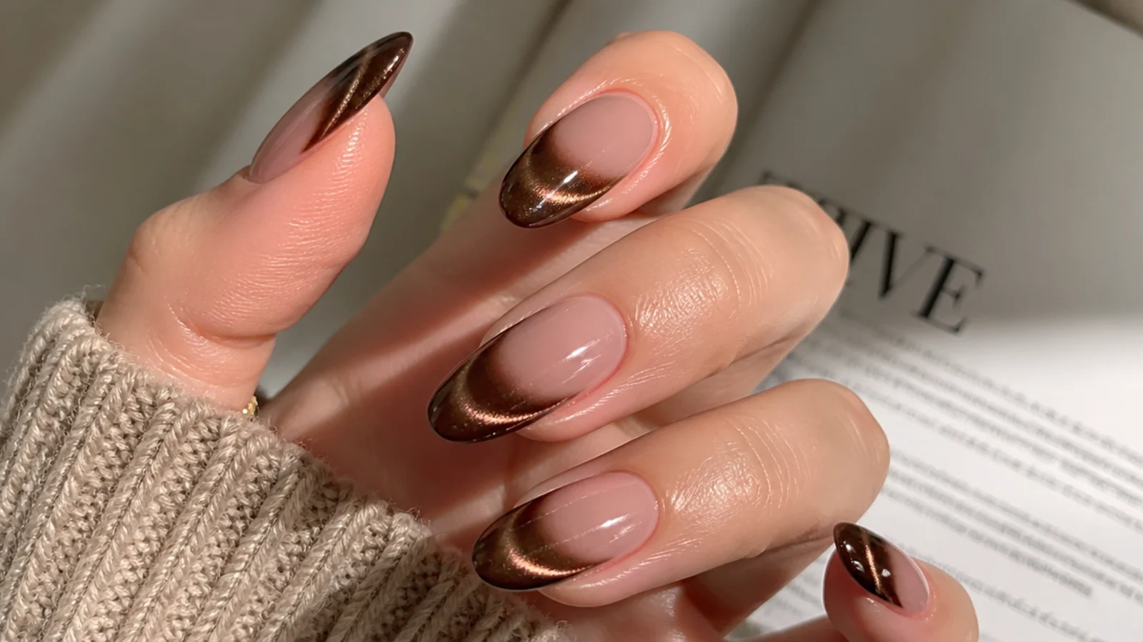 Brown magnetic cat eye french tip nails with a glowing 3D stripe on an almond shape