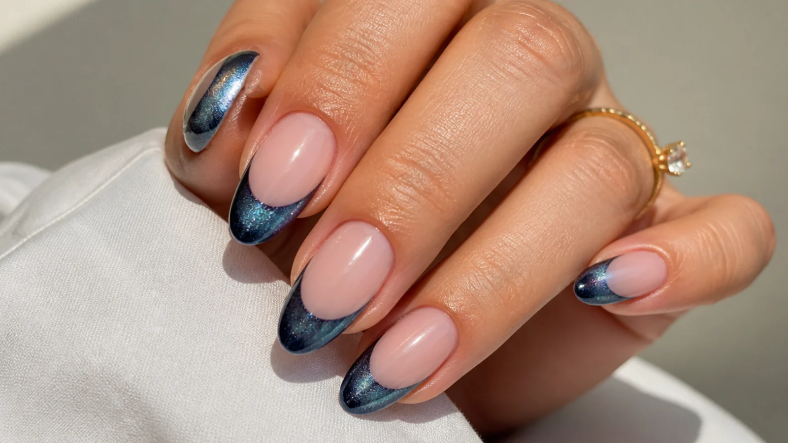 Almond nails with a steel blue magnetic cat eye french tip set on a diagonal