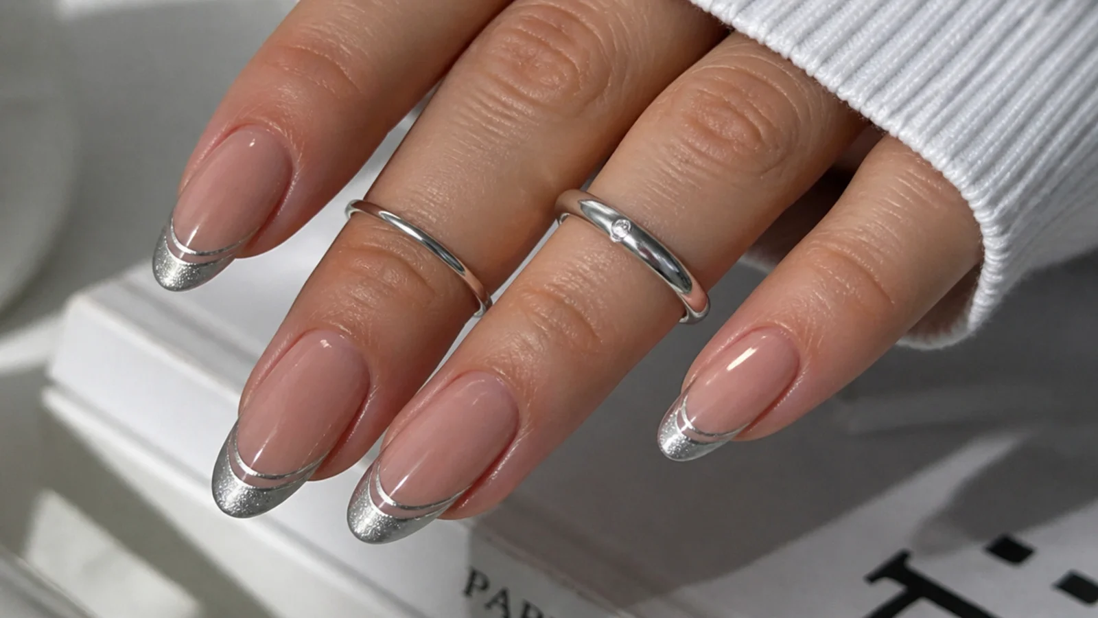Nude nails with a silver magnetic cat eye french tip showing two light stripes