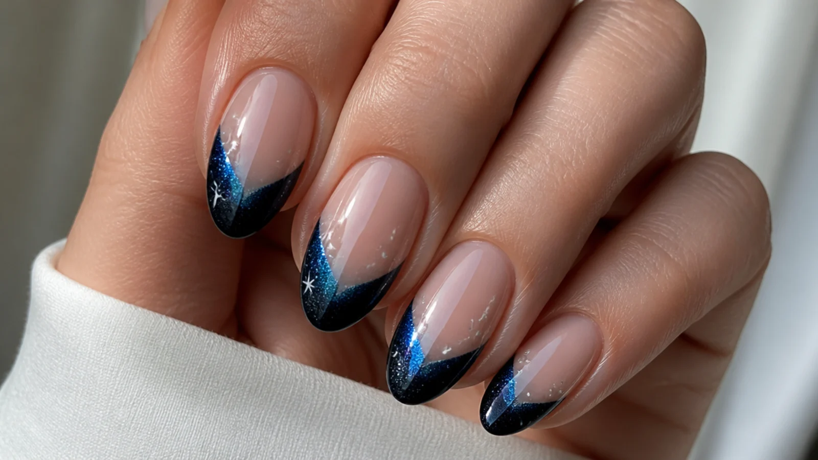 Almond nails with a black-to-blue galaxy magnetic cat eye french tip