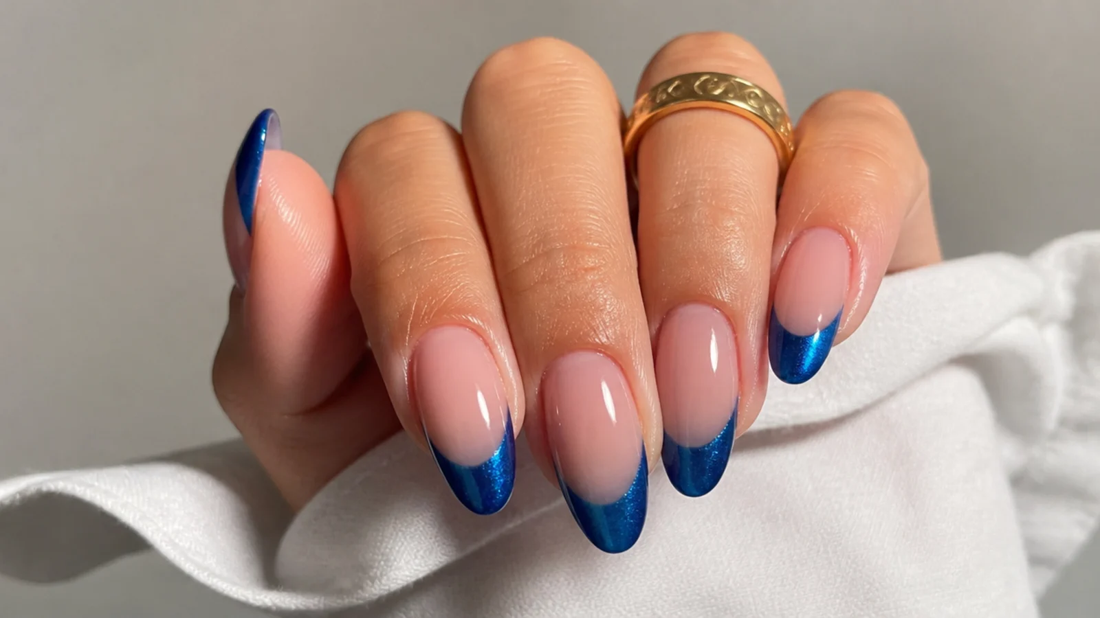 Almond nails with a nude base and a deep sapphire blue magnetic cat eye tip