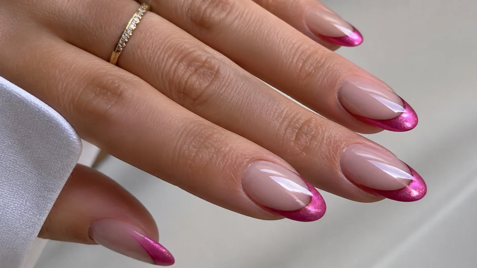Almond nails with a nude base and a vivid hot pink magnetic cat eye tip