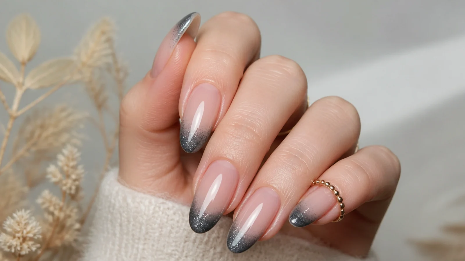 Almond nails with a nude base and a smoky gunmetal gray magnetic cat eye tip