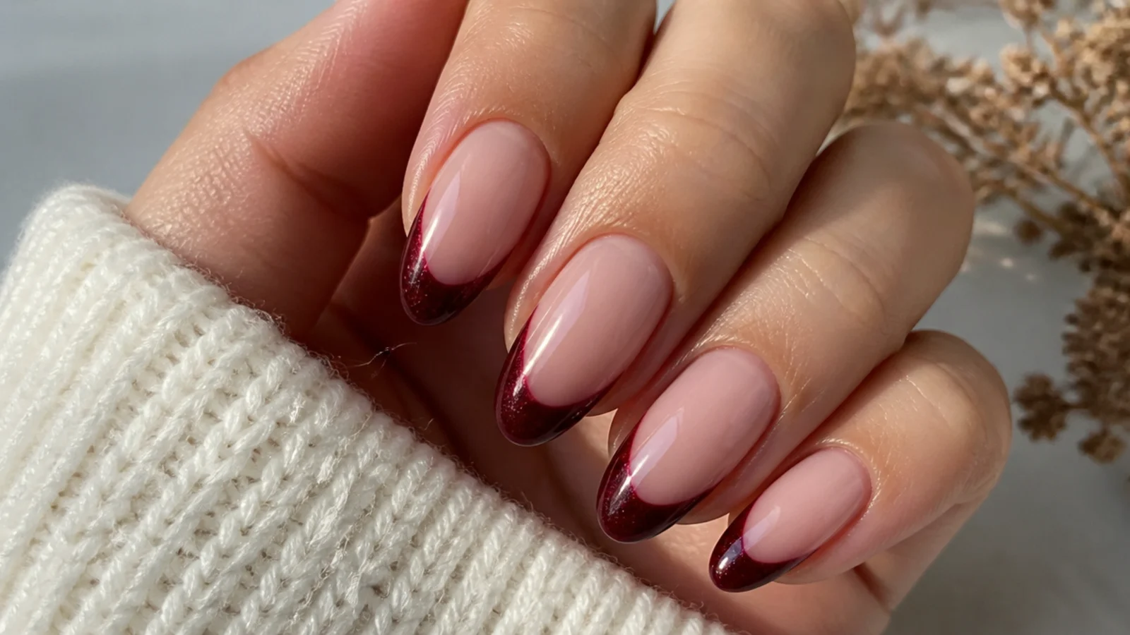 Almond nails with a nude base and a deep burgundy wine magnetic cat eye tip