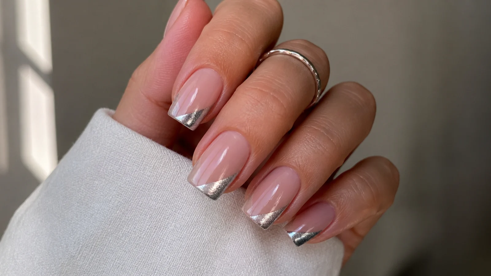 Square nails with a nude base and a slanted diagonal silver magnetic cat eye tip
