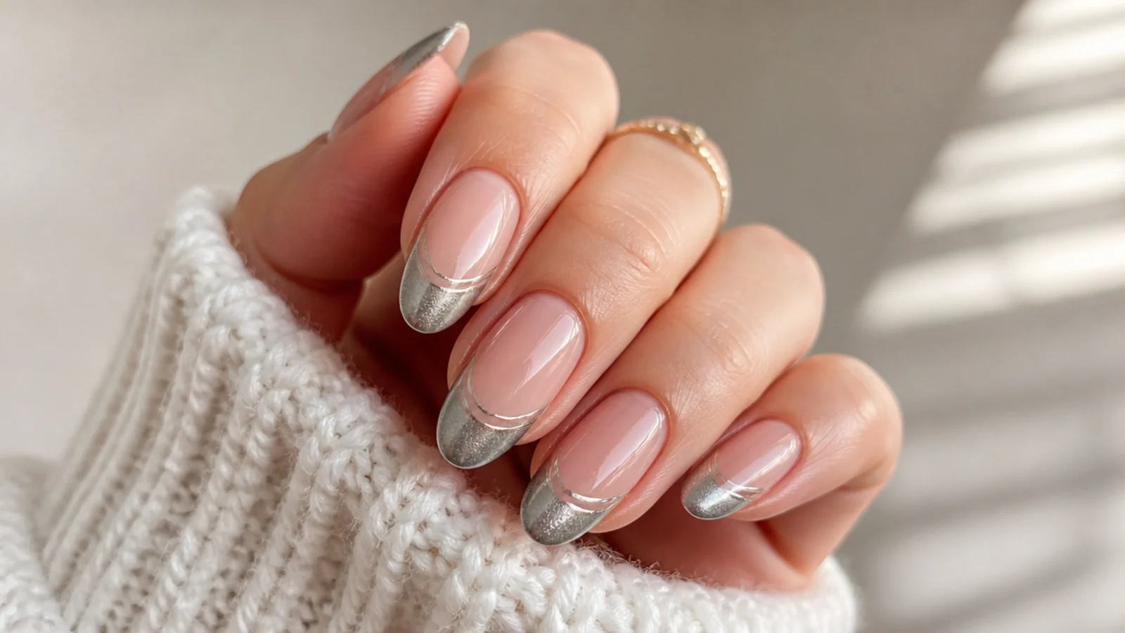 Almond nails with a nude base and a silver cat eye tip showing two parallel light stripes