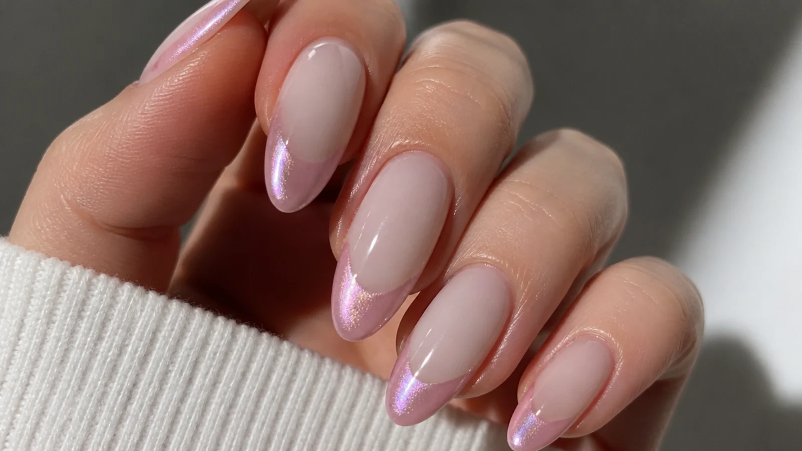Almond nails with a milky base and a glazed pearly pink chrome cat eye tip