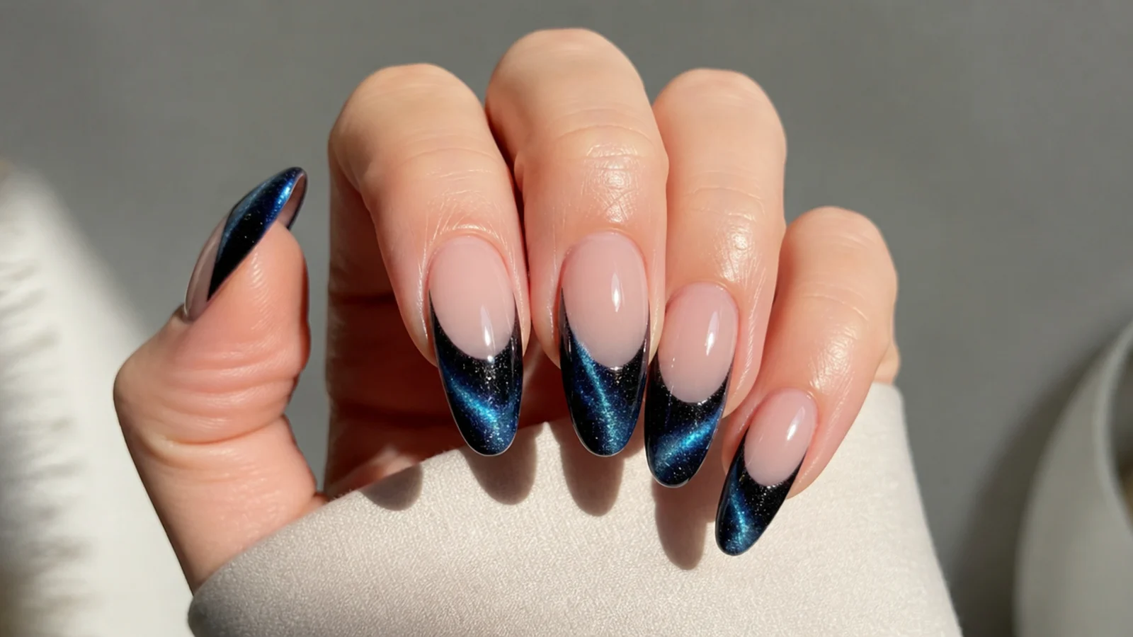 Black to blue shifting magnetic cat eye french tip nails with a bright galaxy stripe
