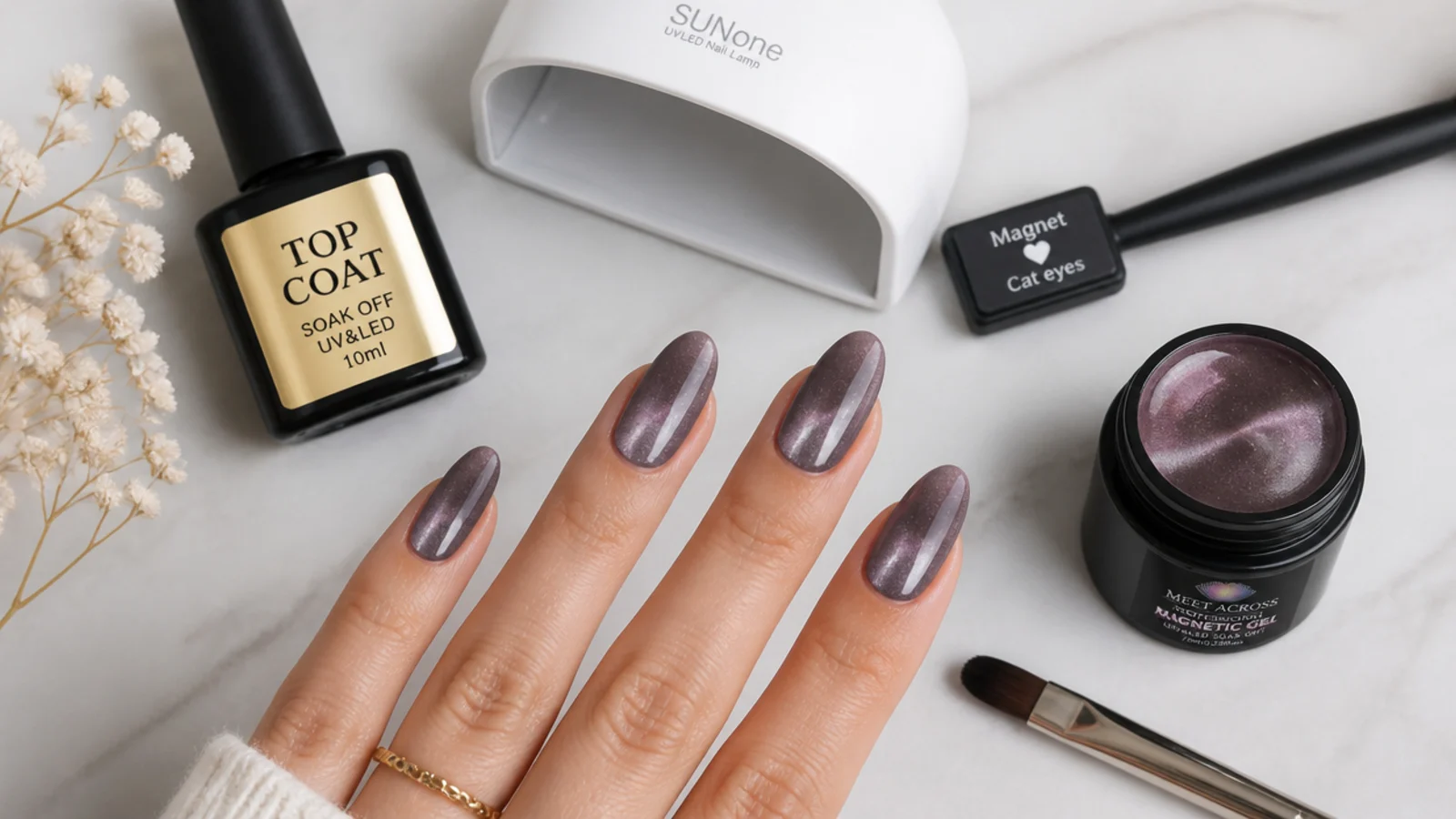 Flat lay of magnetic cat eye gel, a magnet, an LED lamp, brush and top coat