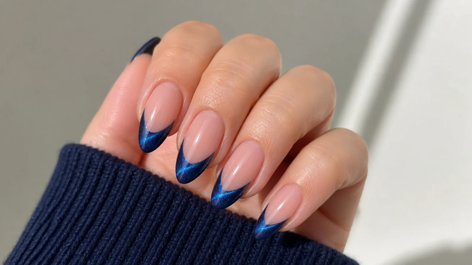 Deep blue magnetic cat eye french tip with a vivid light stripe on almond nails