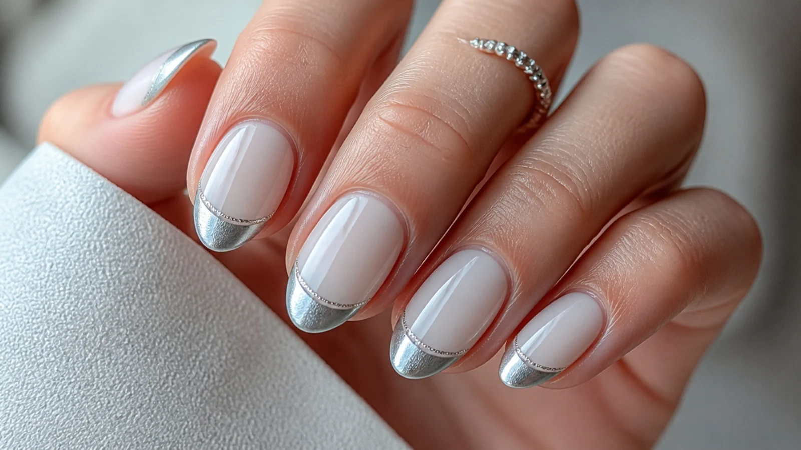 Soft silver chrome french tip nails with a delicate light band on a milky base