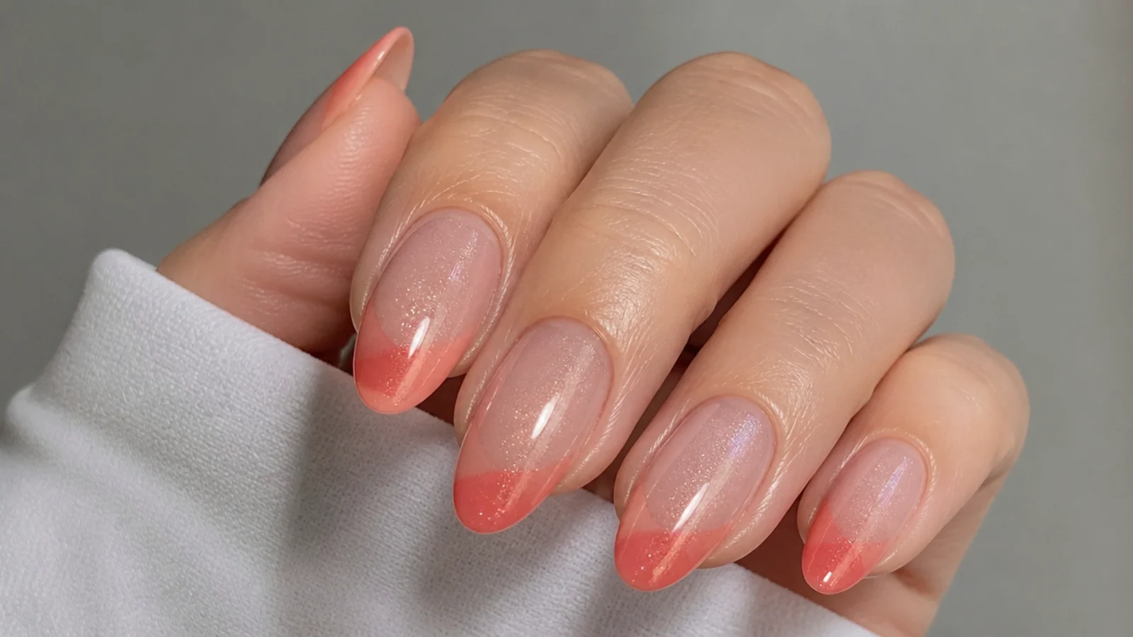 Warm coral pink cat eye french tip nails with a glowing light band