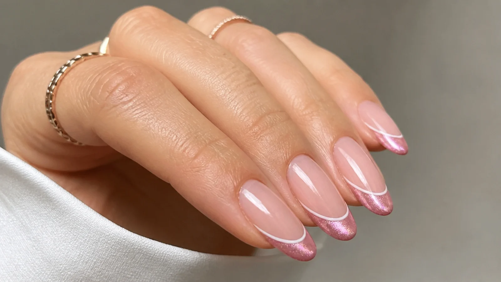 Pink cat eye french tip nails with a thin white outline above the magnetic tip