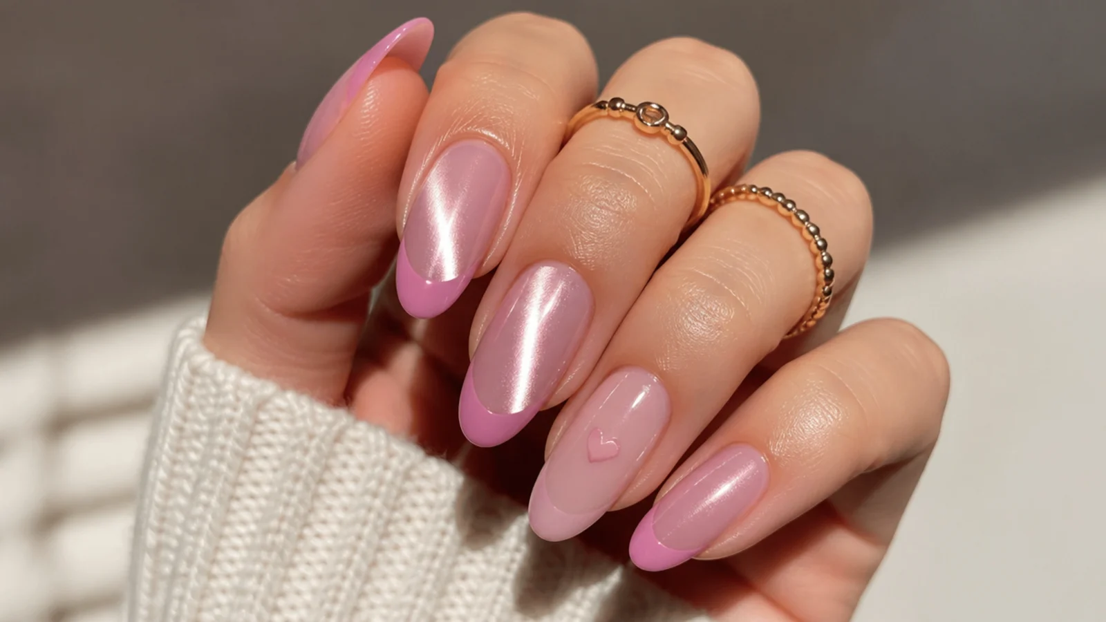 Pink cat eye french tip nails with one small heart accent nail