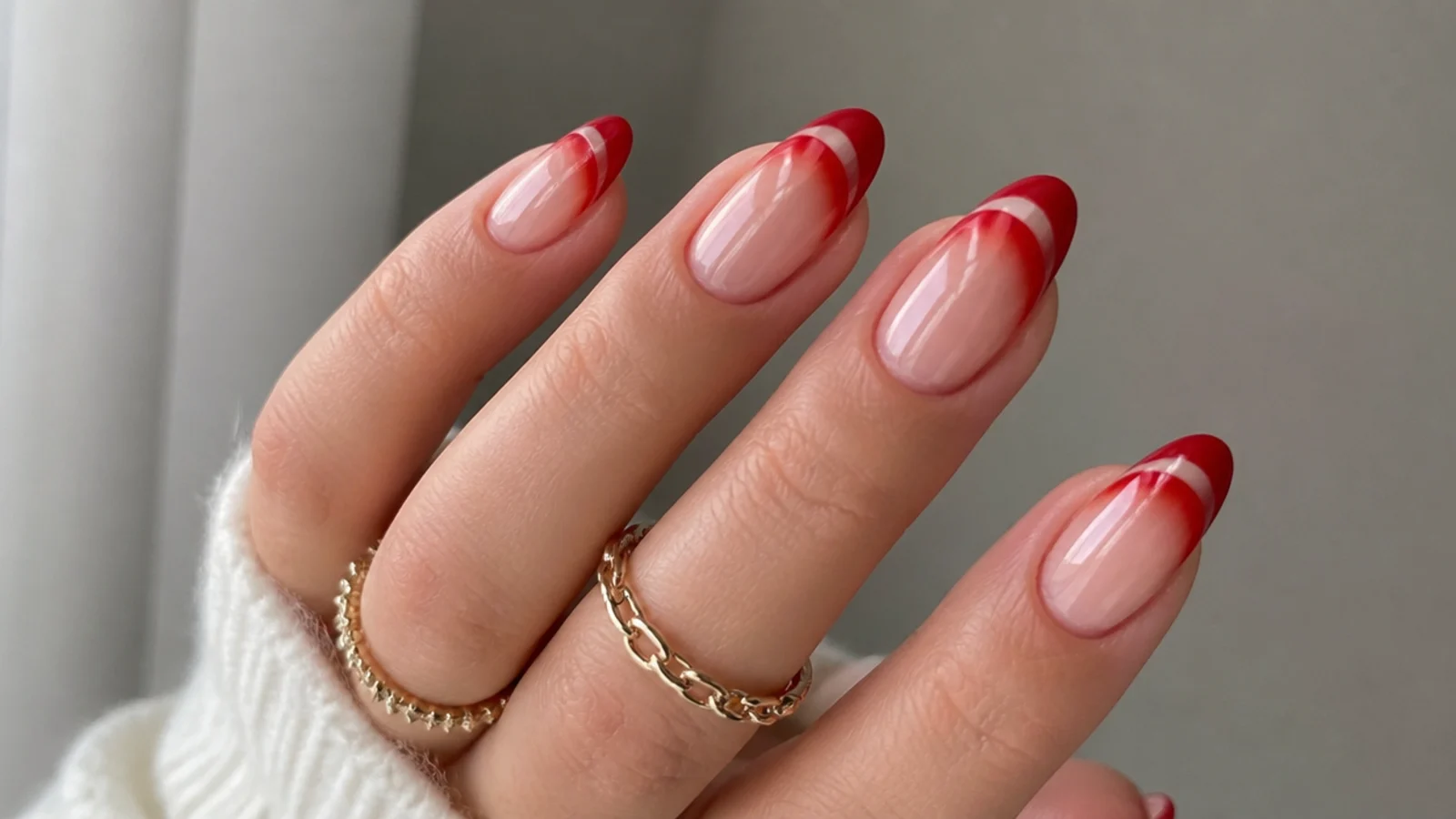 Bright candy apple red cat eye french tip nails on almond shape with a glossy light stripe