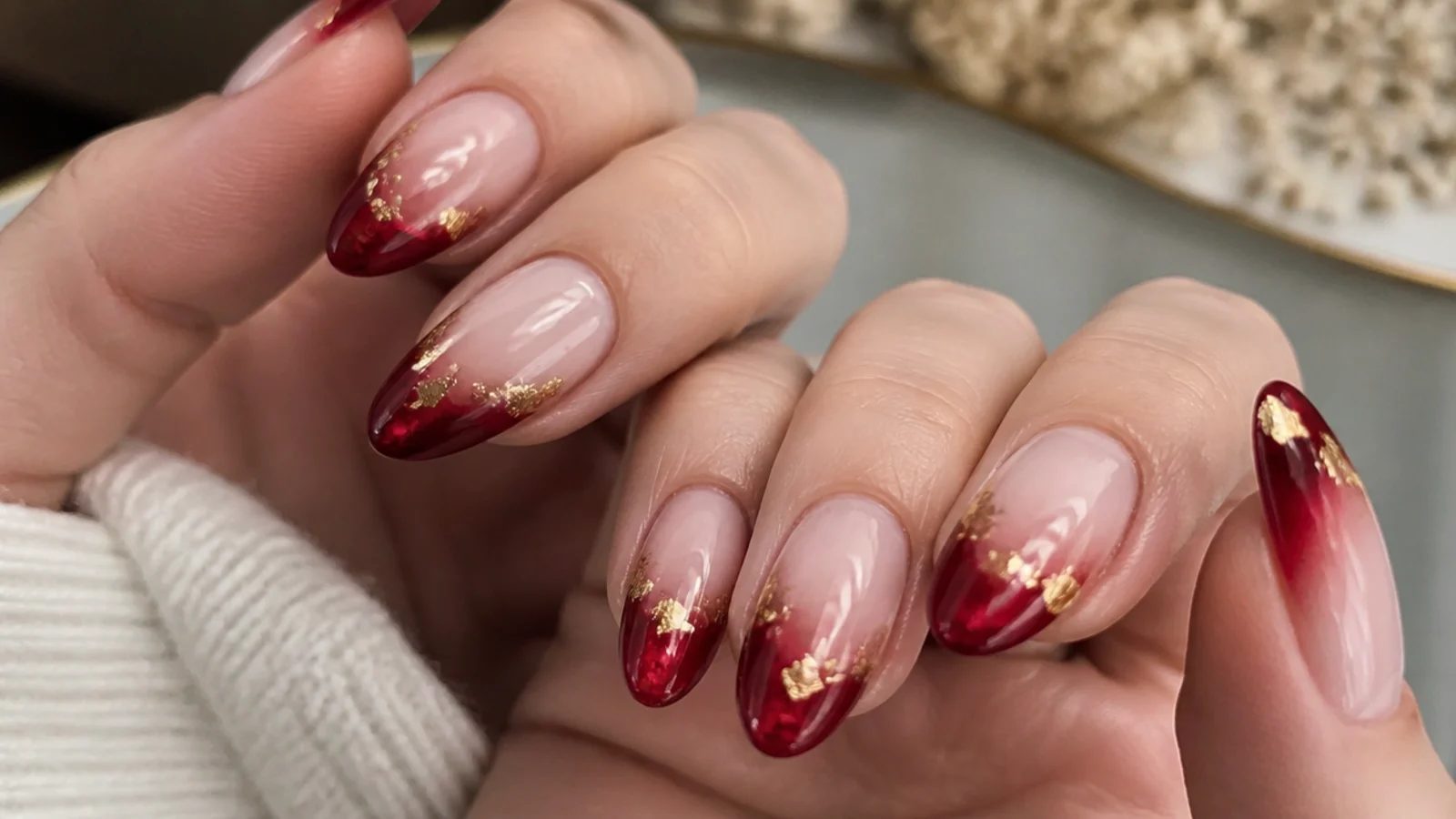 Deep red cat eye french tip nails with gold foil flakes on almond shape