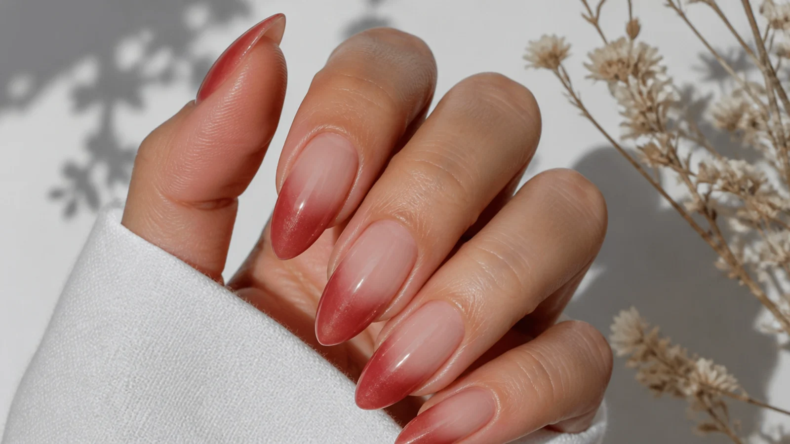 Soft red baby boomer cat eye french tip nails fading into a nude base on almond shape