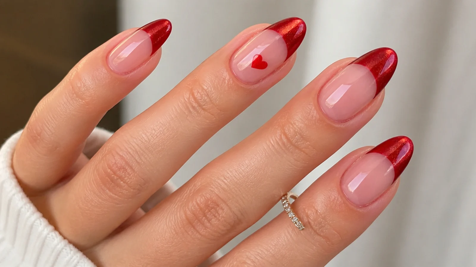 Red cat eye french tip nails with one small red heart accent nail on almond shape
