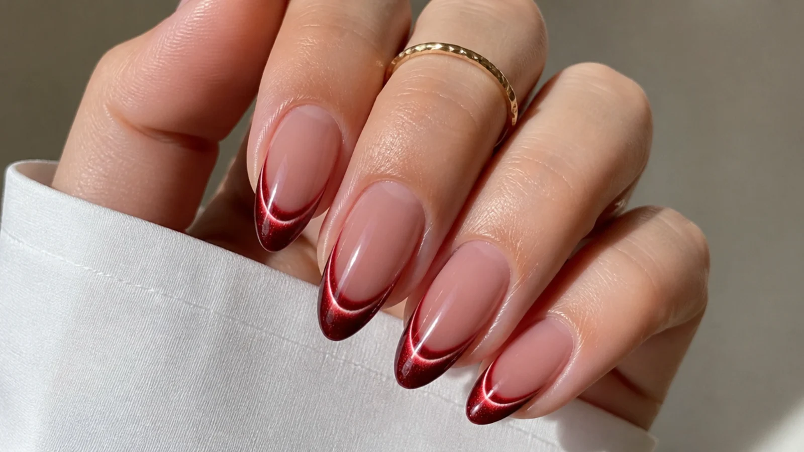 Red cat eye french tip nails with a bright 3D light stripe glowing at each tip on almond shapes