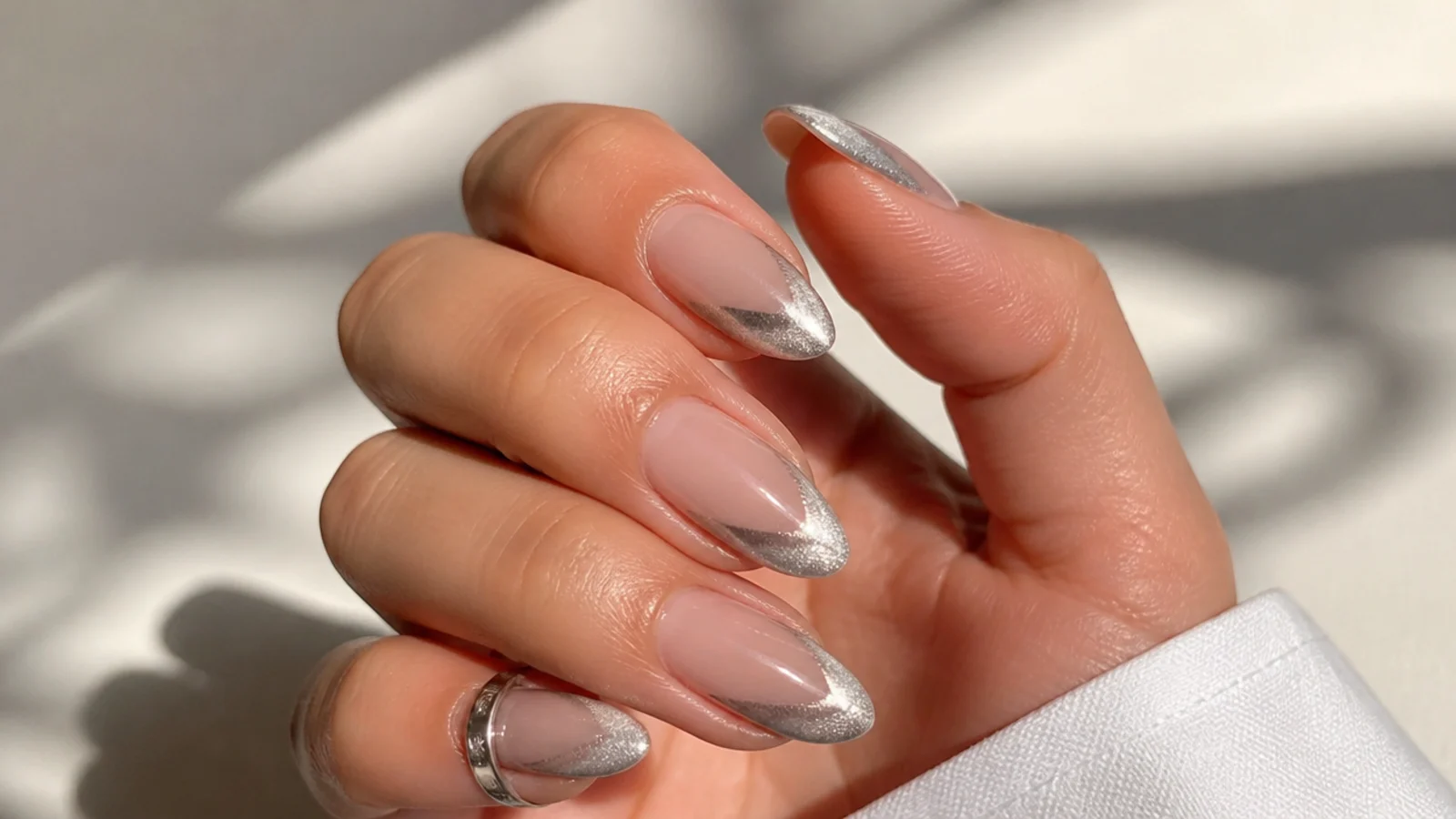 Silver cat eye french tip painted at a diagonal angle on an almond nail