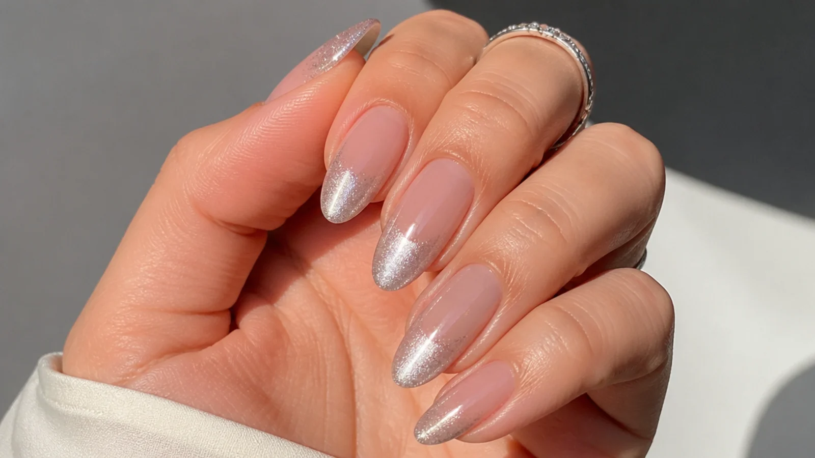 Silver cat eye french tip fading softly into a nude base on almond nails