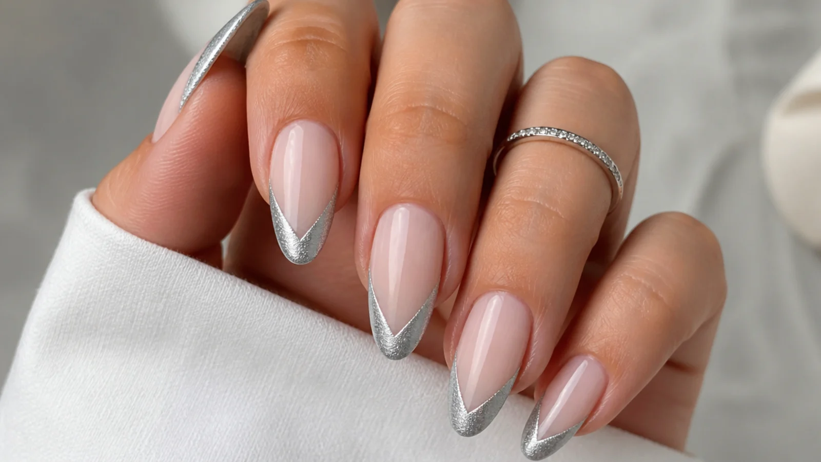 Silver cat eye french tip painted in a V or chevron shape on almond nails