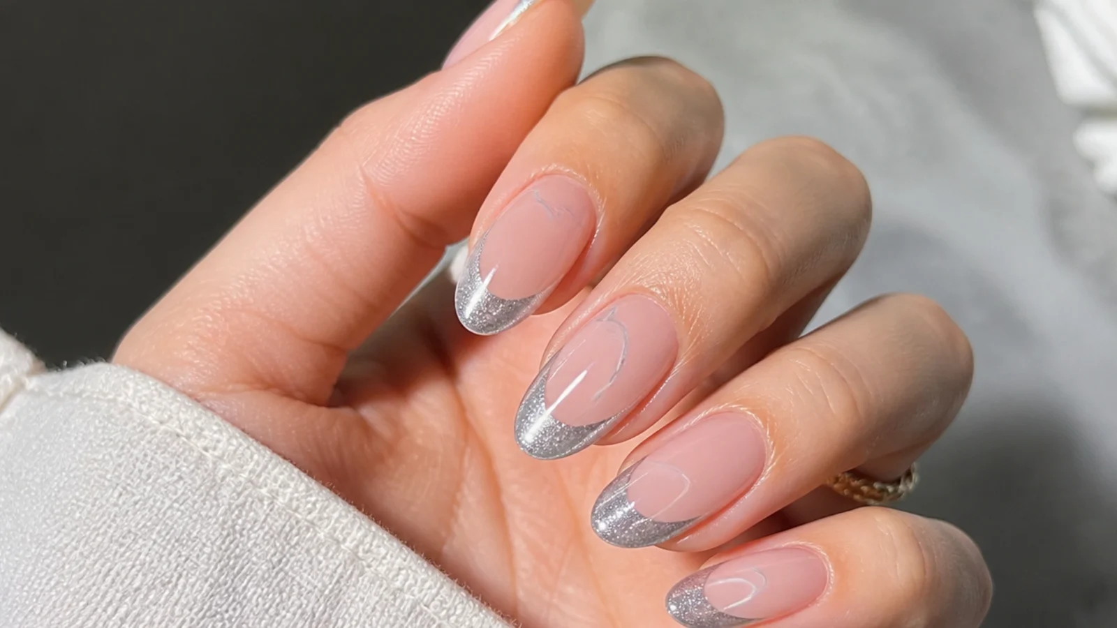 Silver cat eye french tip with a curved swirl of light on an almond nail