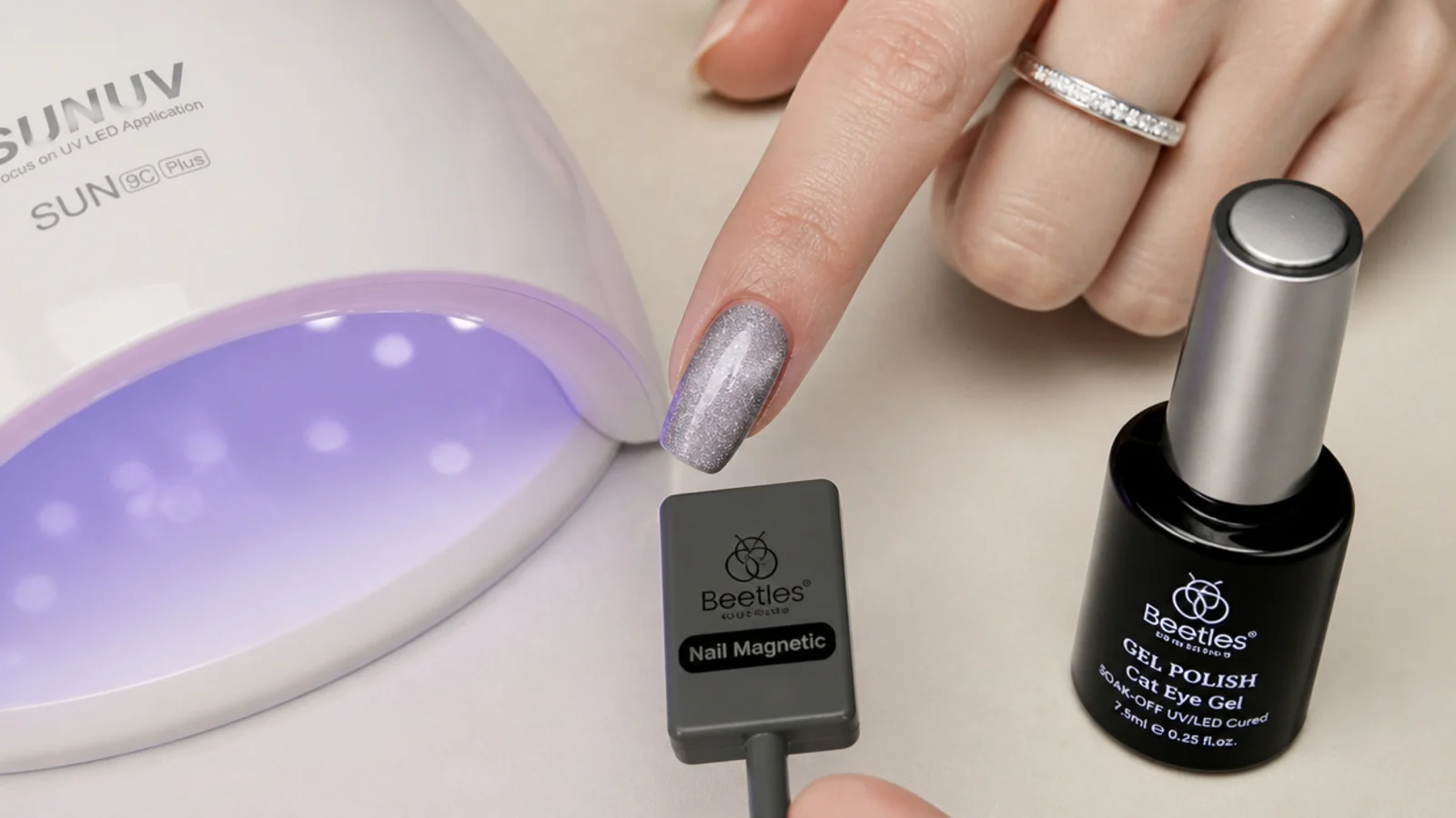 Silver magnetic gel, a magnet and a lamp laid out with a nail mid-magnetize