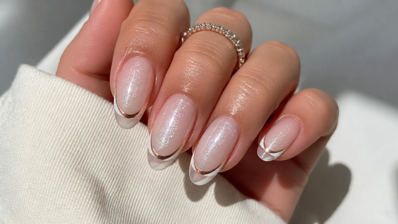 White cat eye french tip nails with a warm rose-gold toned light band