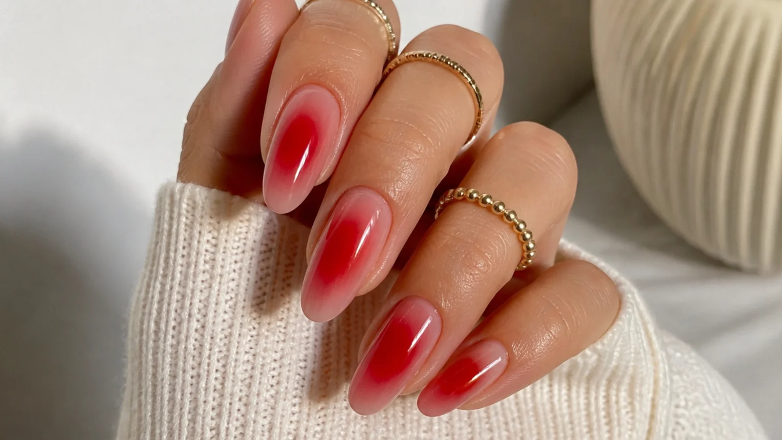 Long almond nails with a cherry red aura halo diffusing into a sheer nude base