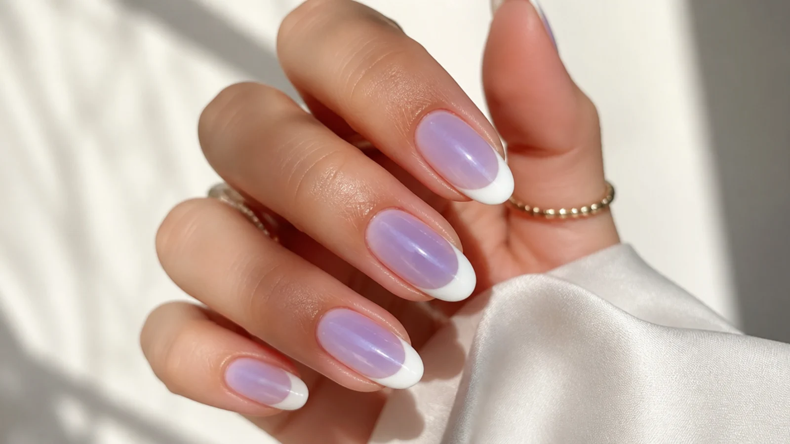 Almond nails with a lilac aura glowing from the nail bed under a crisp white French tip