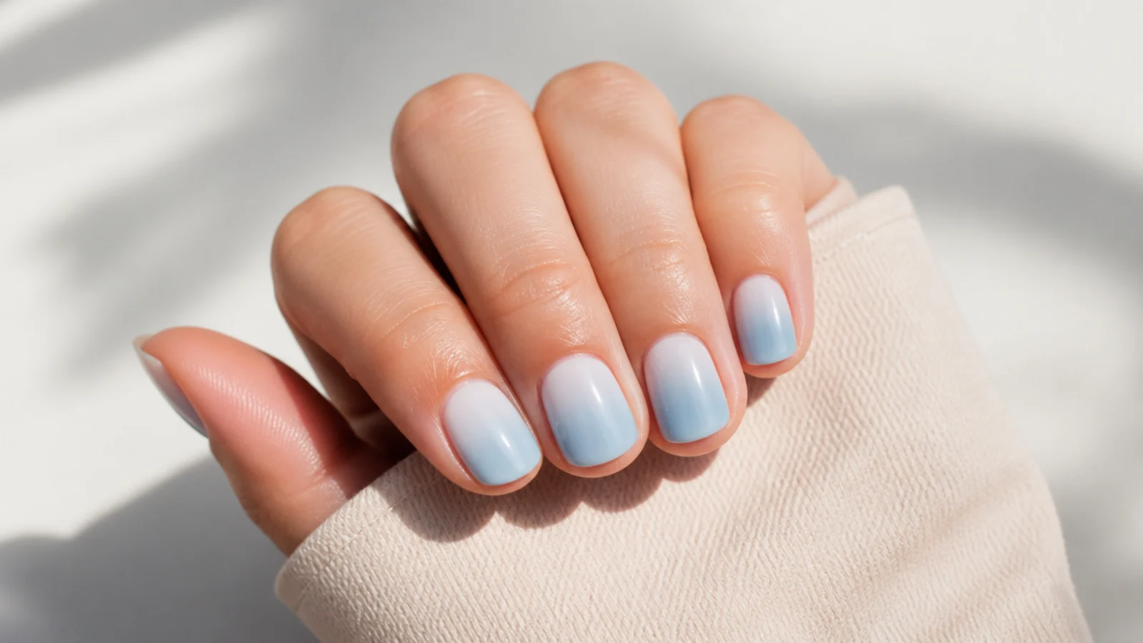 Short blue aura nails with a baby blue center fading into soft white toward the cuticle