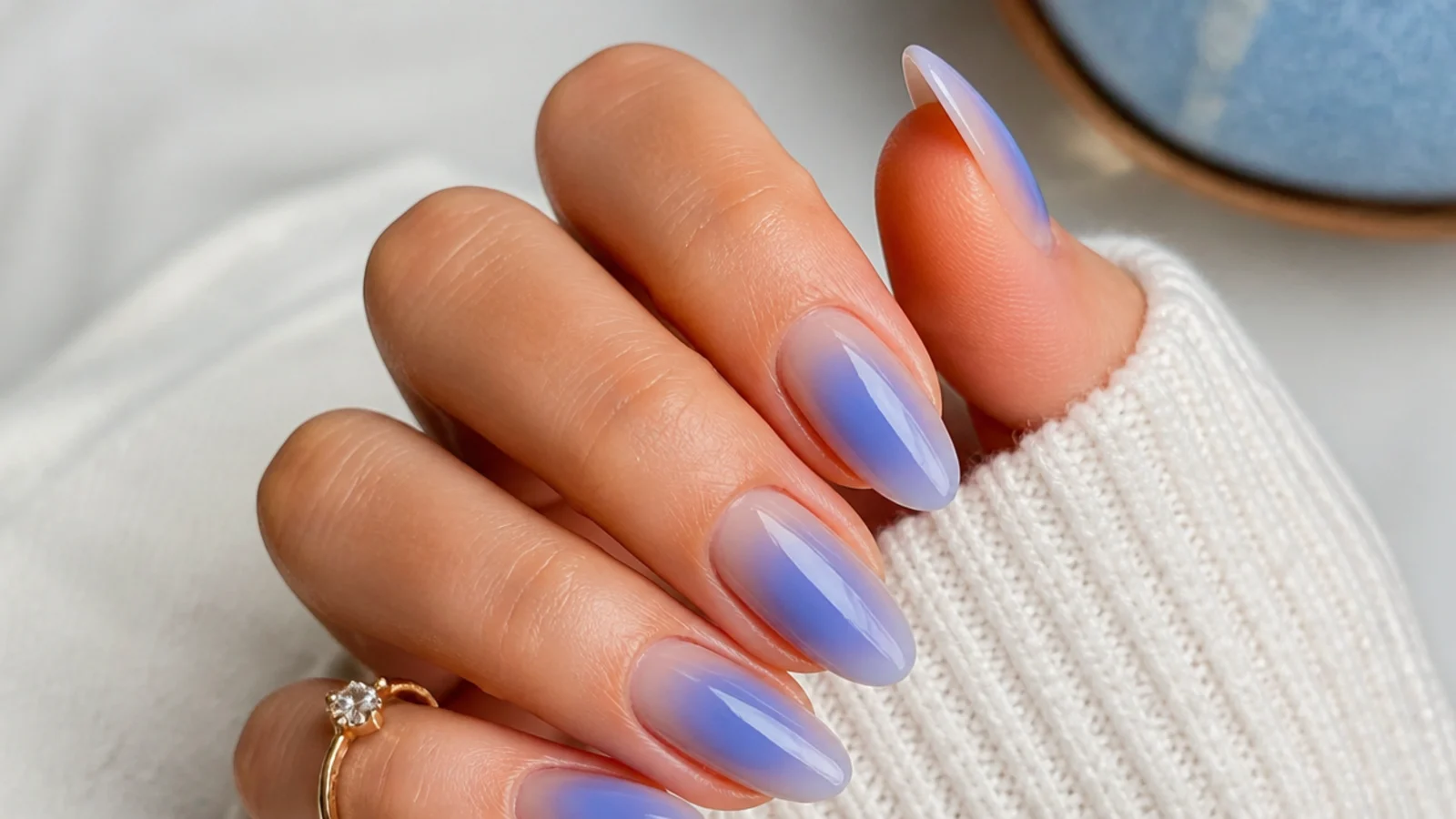 Medium almond nails with a cornflower blue aura glow over a sheer nude base