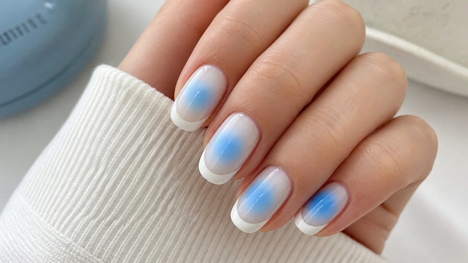Blue aura nails with a crisp white French tip painted over a powder blue center glow