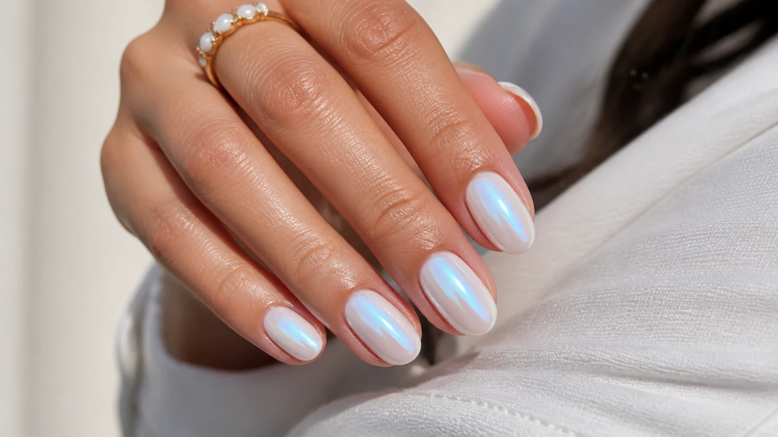 Short almond nails with blue chrome over a milky white base giving a pearly glazed sheen