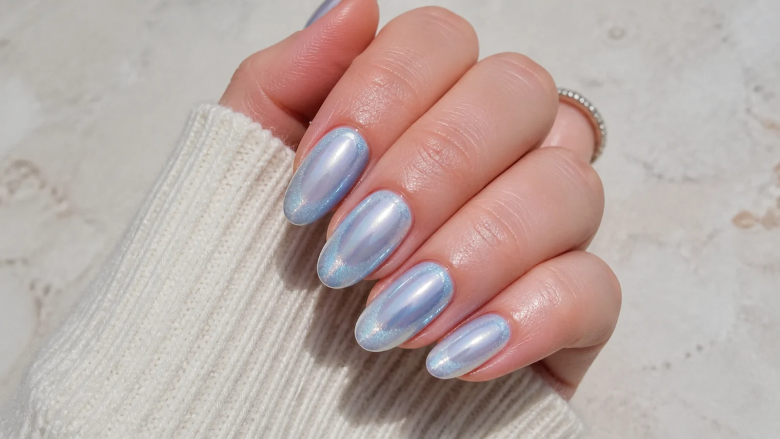 Ice blue chrome aura nails with a frosted silver-blue halo on almond shaped nails
