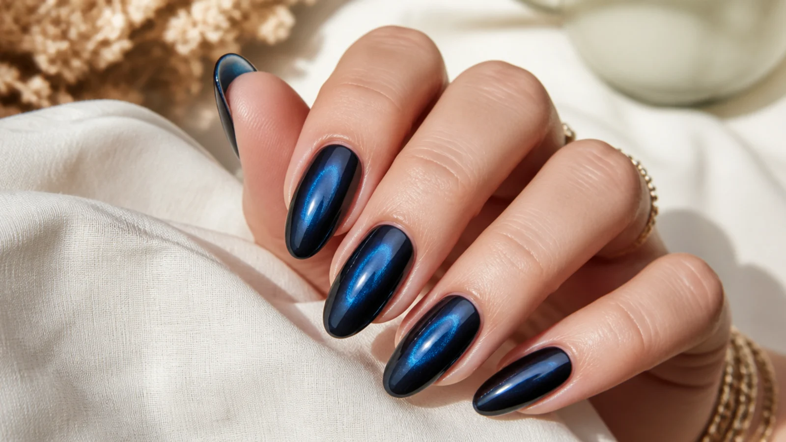 Navy chrome aura nails with a deep blue mirror glow on medium length almond nails