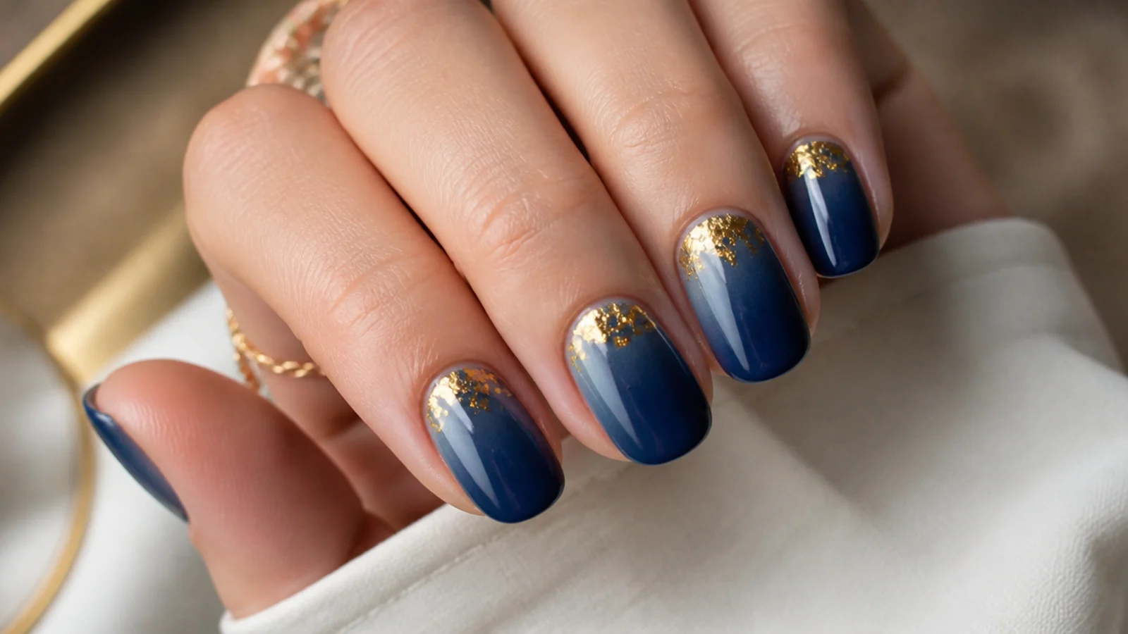Navy blue aura nails with torn gold foil flakes pressed near the cuticle area