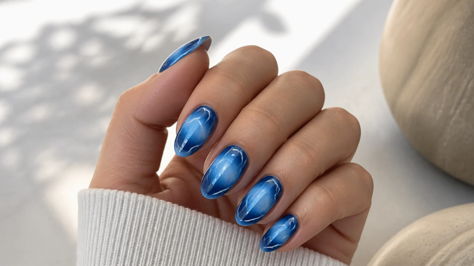 Cobalt blue aura nails with thin white line swirls looping across the glowing center