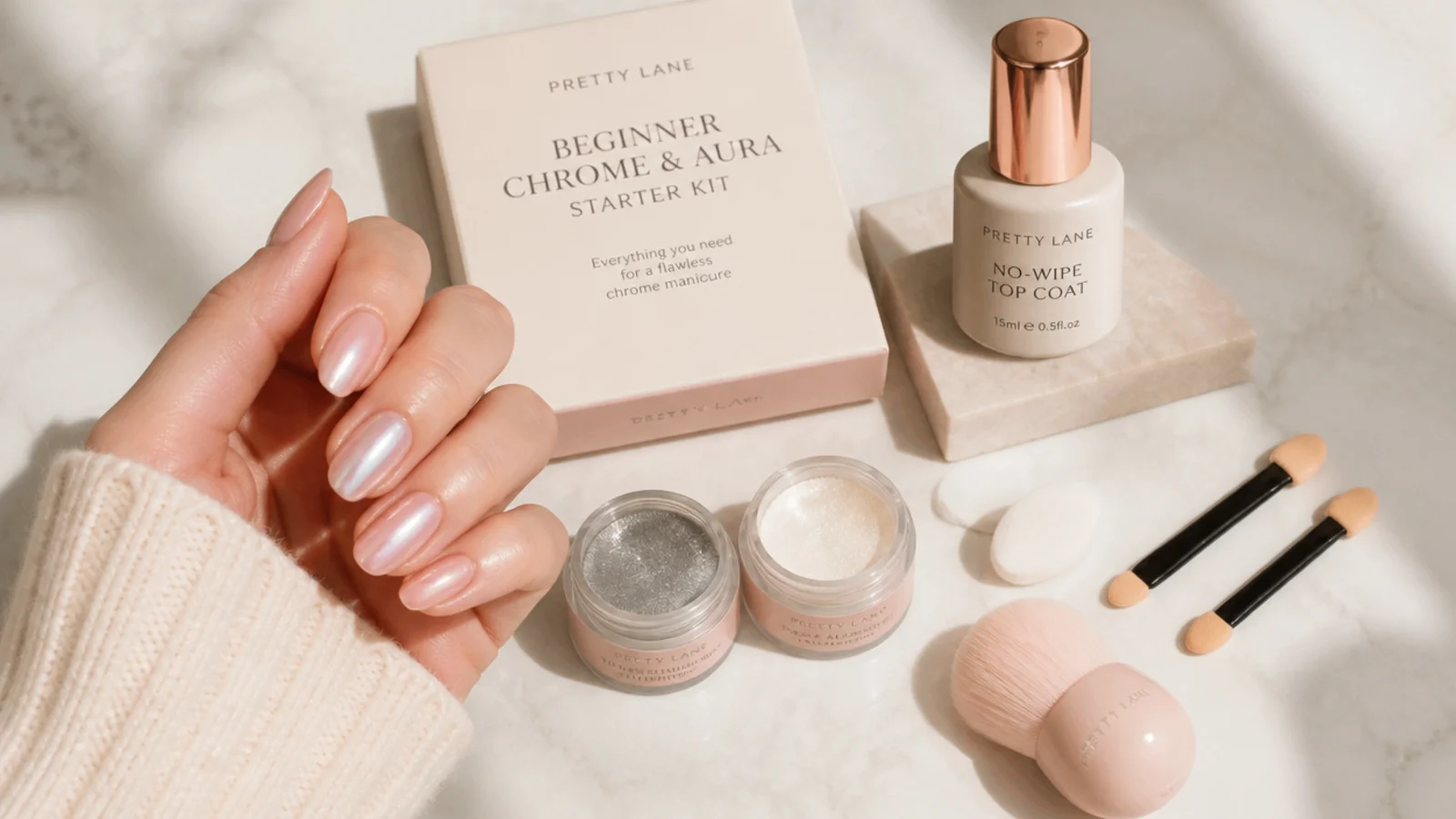 A beginner chrome and aura starter kit flat lay with no-wipe top coat, silver and pearl powders, sponges and applicators