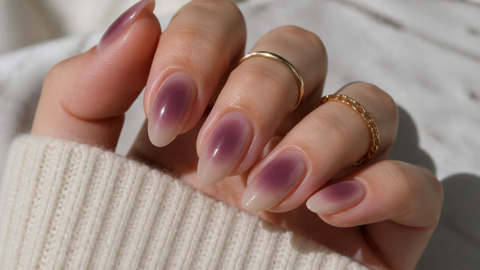 Medium almond nails with a warm plum aura halo blended over a beige base