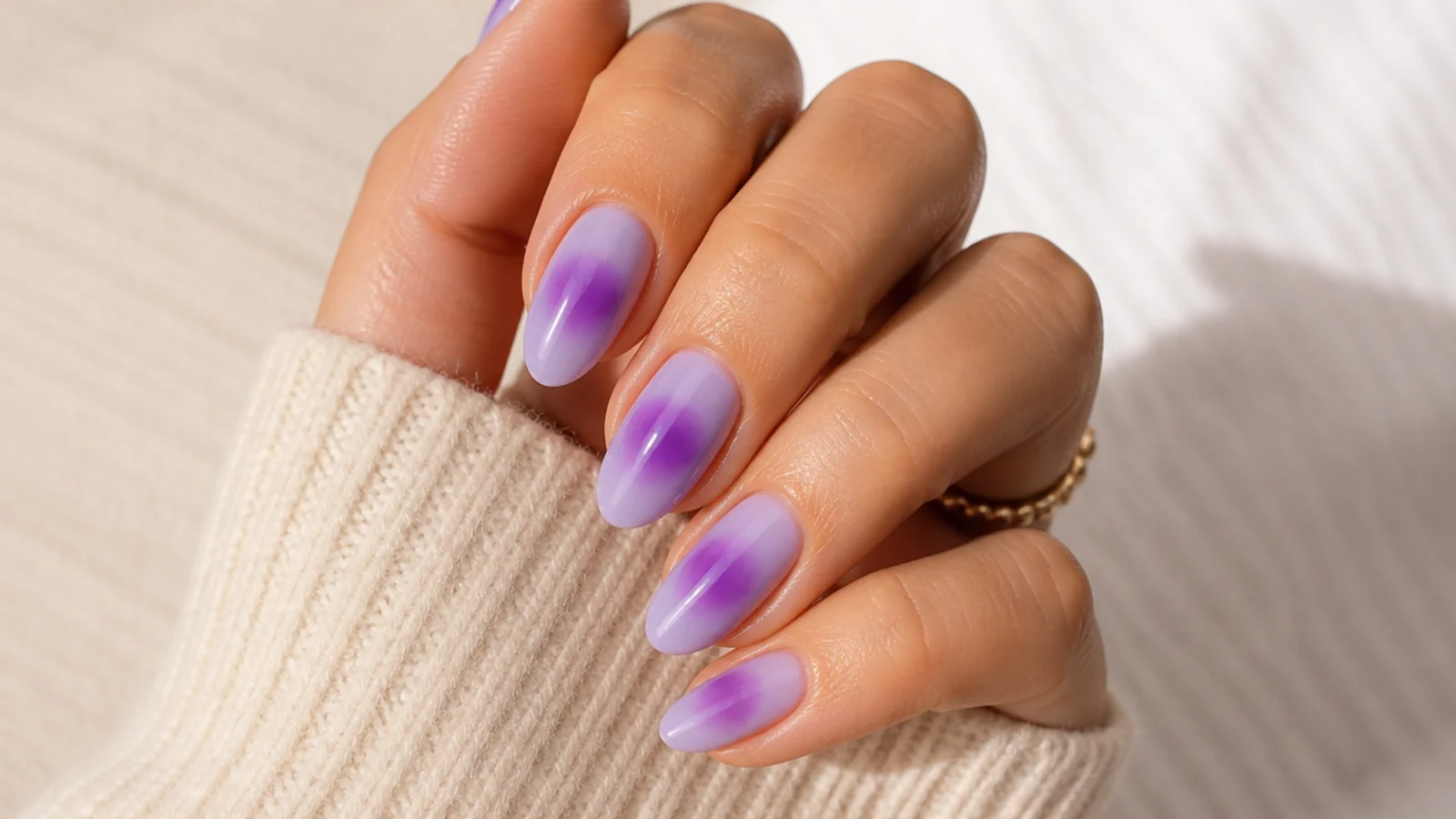 Almond purple aura nails with a violet halo glowing from the center of a sheer lilac base