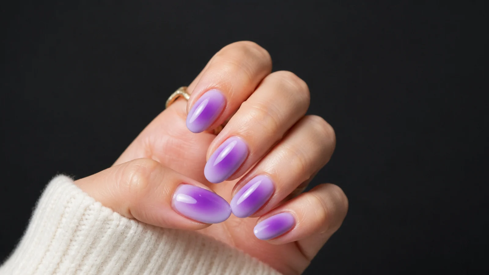 Violet aura nails photographed against a soft dark background showing the glowing halo