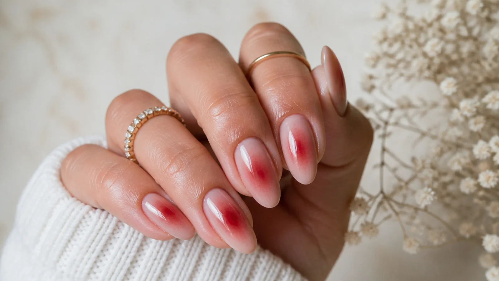 Almond red aura nails with a cherry red glow blurred outward from the center of a sheer nude base