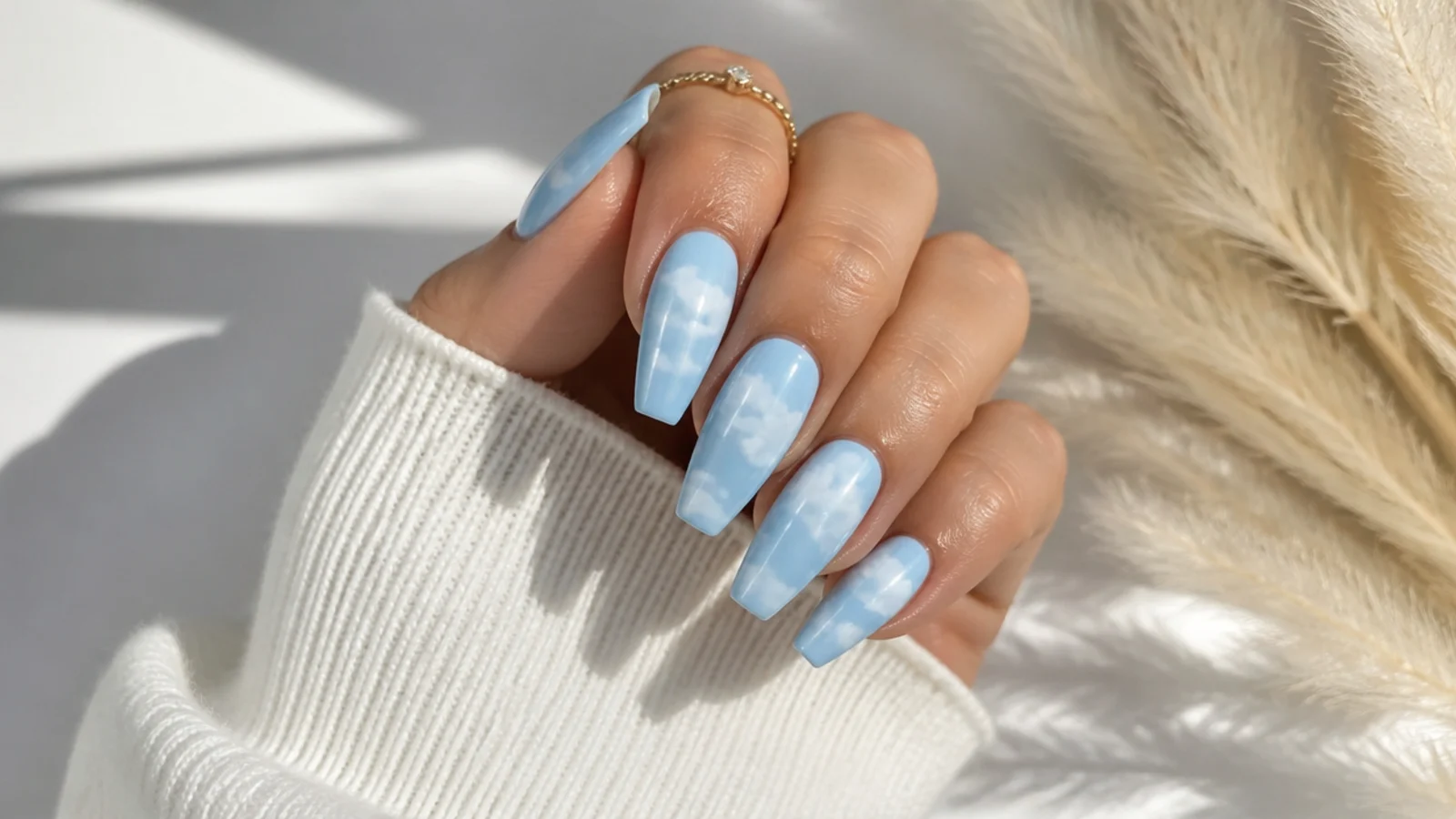 Baby blue coffin nails with soft white painted clouds across the tips