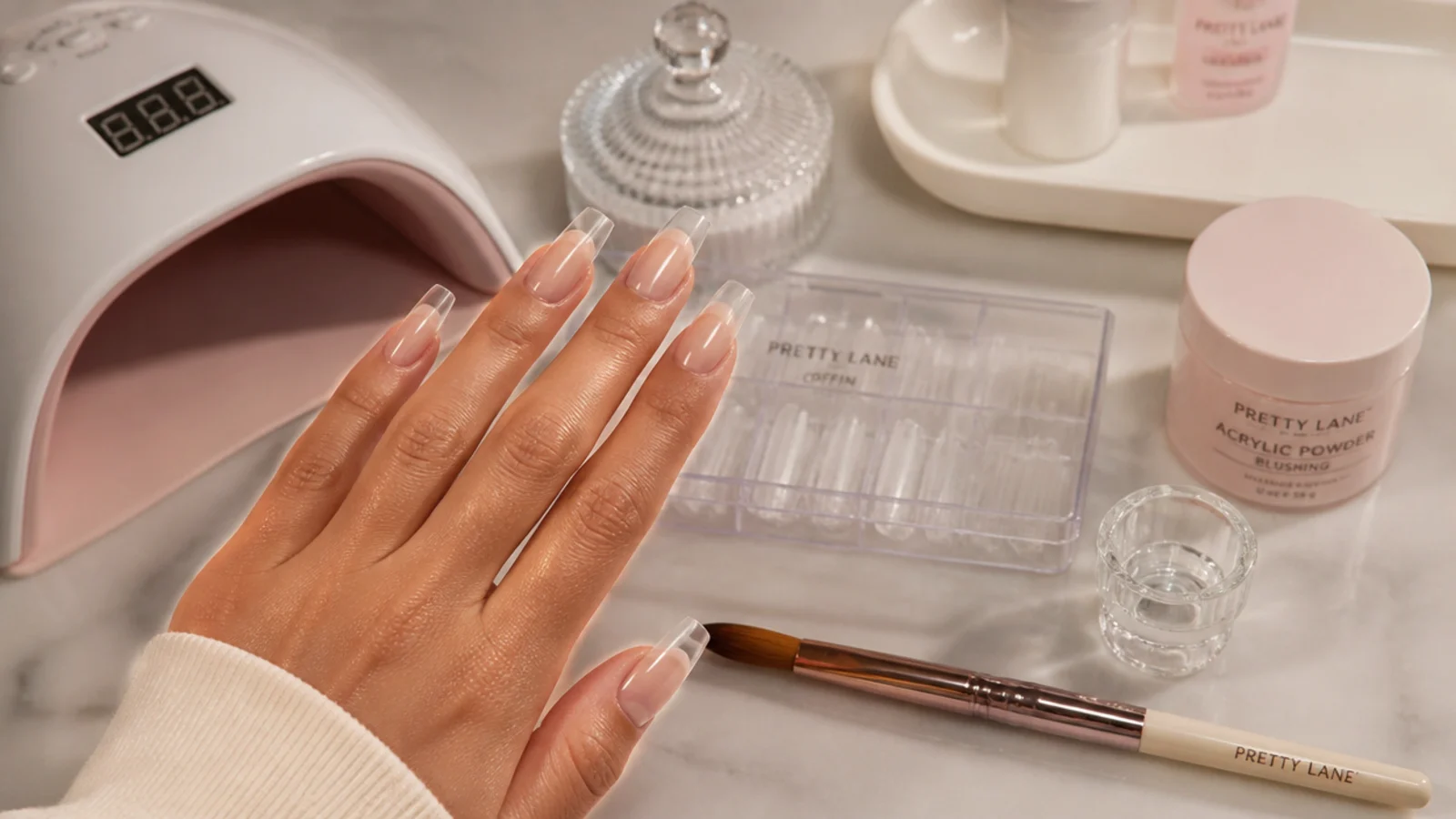 Nail salon station with acrylic brush, tips and lamp set up for a coffin nail full set